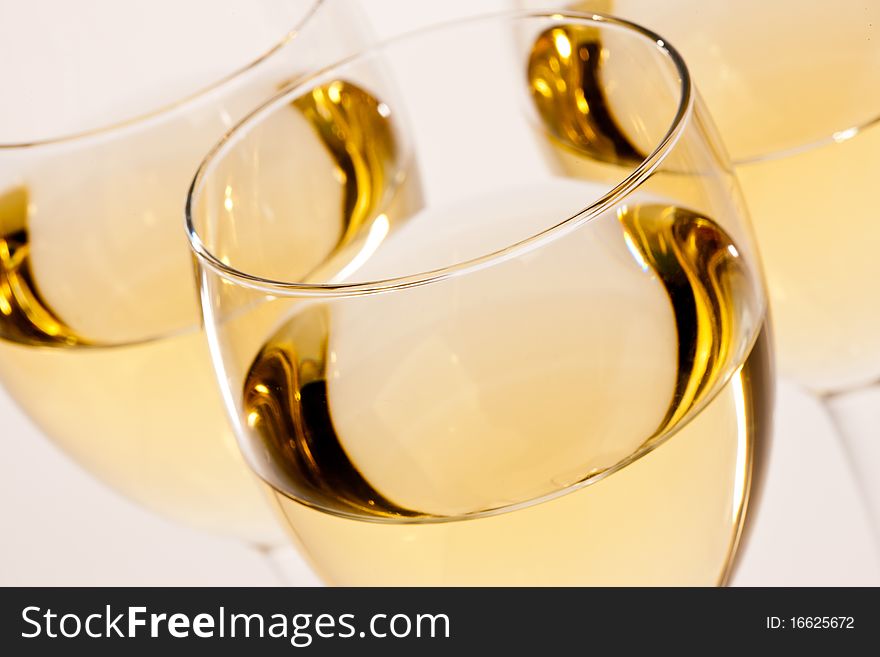 Three glasses with white wine over light bsckground