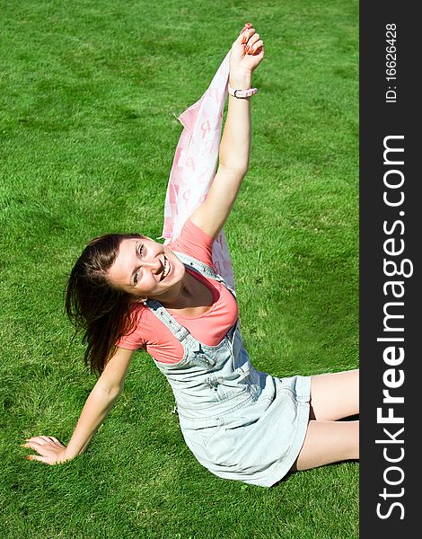 Happy young brunette with a handkerchief resting on the lawn in summer. Happy young brunette with a handkerchief resting on the lawn in summer