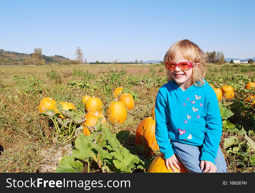 Cute Little Girl Sitting On The Pumpkin