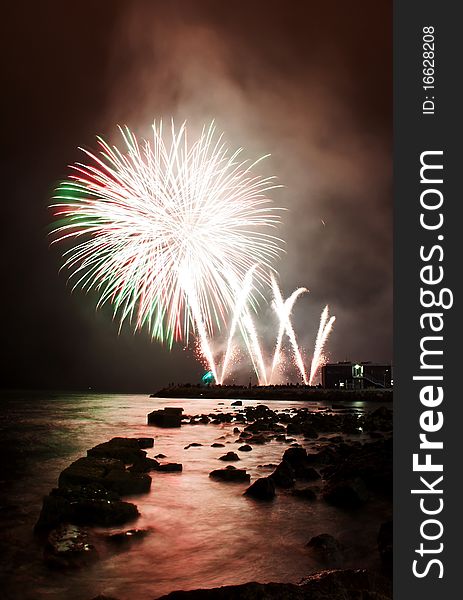 White fireworks launched at the shoreline of the harbor