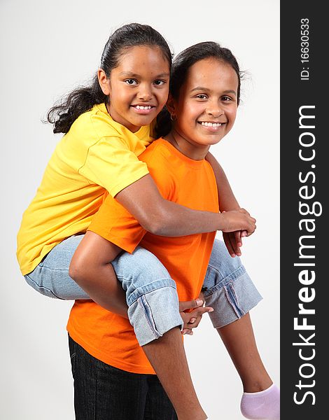 Fun piggy back ride from two happy young school girl friends together in studio - . Fun piggy back ride from two happy young school girl friends together in studio -