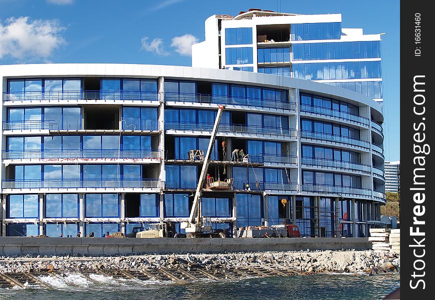 Building of the house with the crane against the dark blue sky. Building of the house with the crane against the dark blue sky