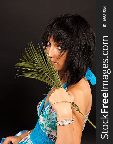 Beautiful girl holding a big green palm leaf. She is isolated on a black background. Beautiful girl holding a big green palm leaf. She is isolated on a black background.