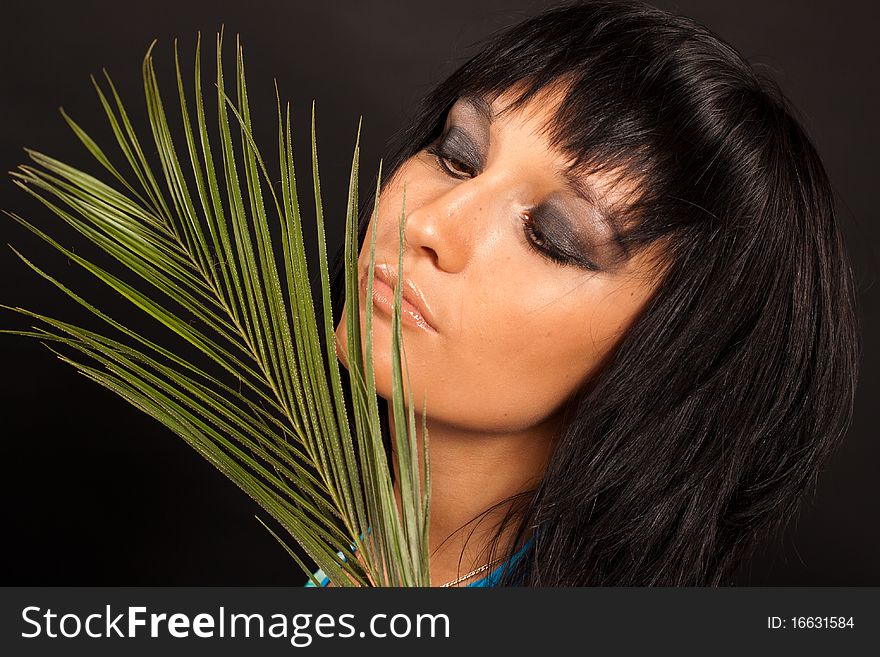 Beautiful girl holding a big green palm leaf. She is isolated on a black background. Beautiful girl holding a big green palm leaf. She is isolated on a black background.