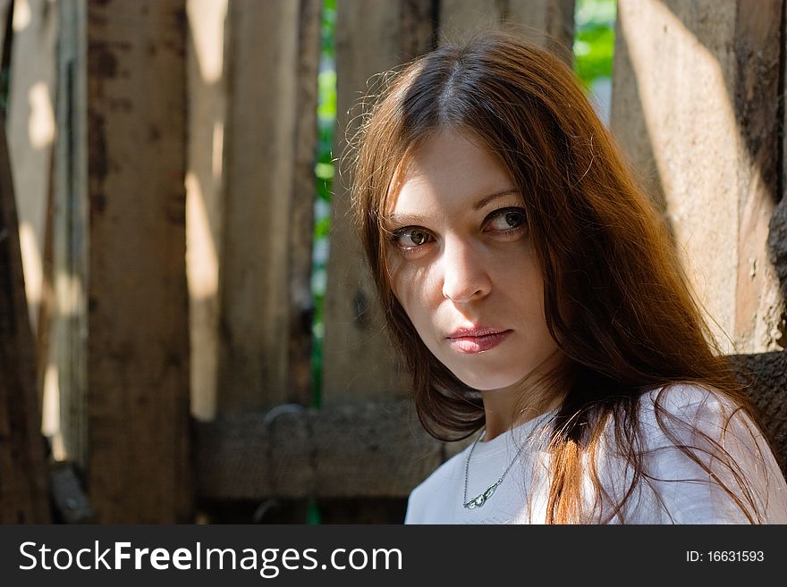 Close-up of beautiful woman against a old wooden wall. Close-up of beautiful woman against a old wooden wall