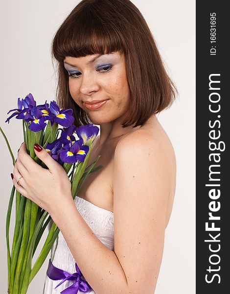 Beautiful girl holding a bouquet of irises. She is in studio isolated on a white background. Beautiful girl holding a bouquet of irises. She is in studio isolated on a white background