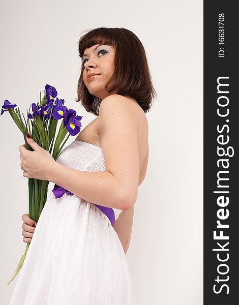 Beautiful girl holding a bouquet of irises. She is in studio isolated on a white background. Beautiful girl holding a bouquet of irises. She is in studio isolated on a white background