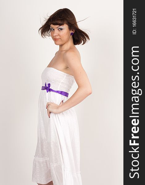 A girl in a white evening dress with a purple ribbon on a white background. A girl in a white evening dress with a purple ribbon on a white background