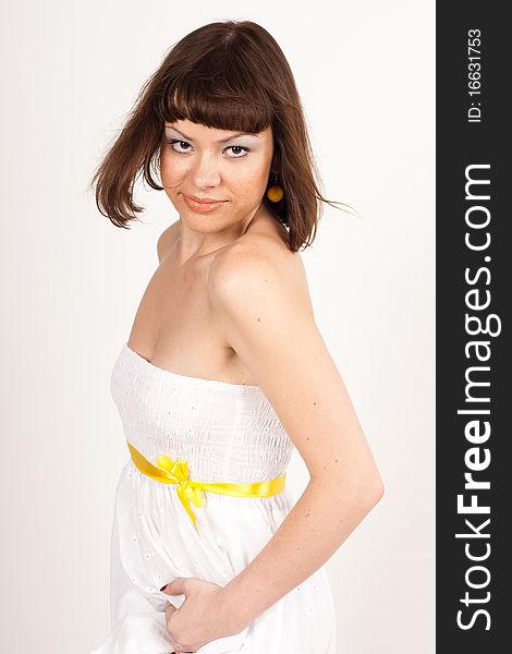 A girl in a white evening dress with a yellow ribbon on a white background. A girl in a white evening dress with a yellow ribbon on a white background