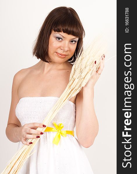 Beautiful brunette girl in white dress with ears of wheat in her hair isolated on the white background. Beautiful brunette girl in white dress with ears of wheat in her hair isolated on the white background