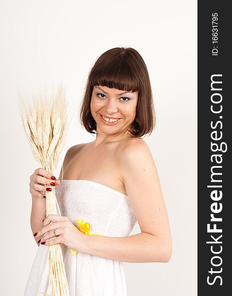 Beautiful brunette girl with ears of wheat in her hair isolated on the white background