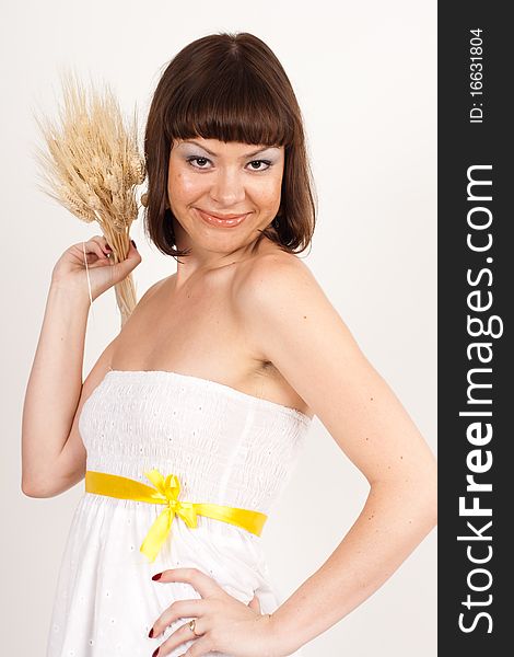 Beautiful brunette girl with ears of wheat in her hair isolated on the white background