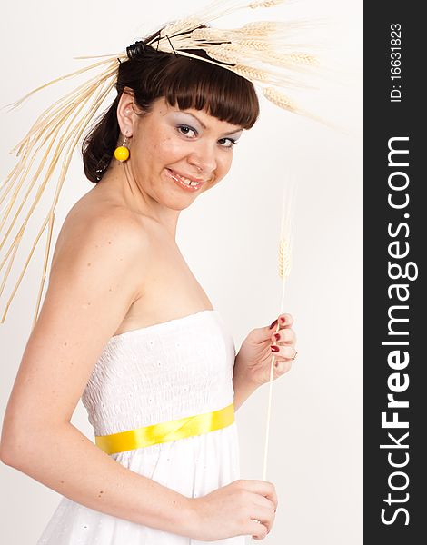 Beautiful brunette girl with ears of wheat in her hair isolated on the white background