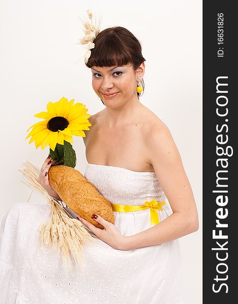 Girl with bread, sunflower and ears of wheat
