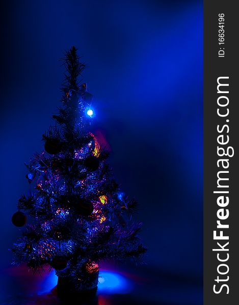 Christmas tree is richly decorated with a blue background