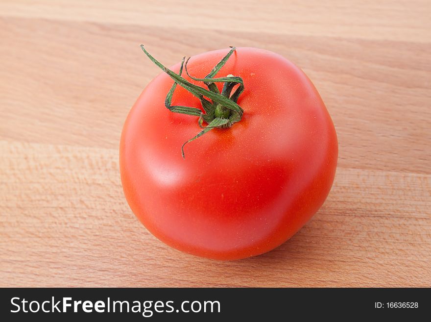 Red tomato on brown kitchen board. Horizontal image