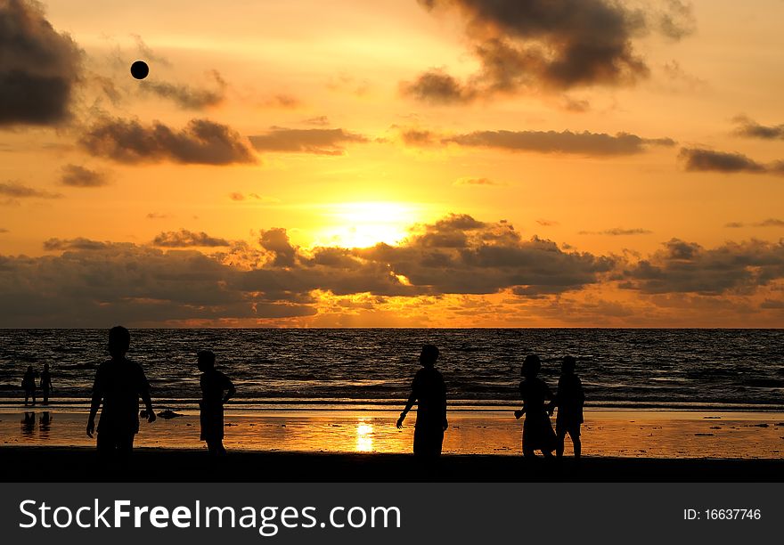 Football players playing under the sunset at the beach. Football players playing under the sunset at the beach