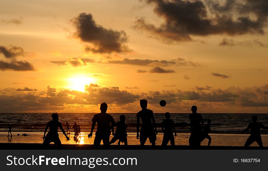 Football players playing under the sunset at the beach. Football players playing under the sunset at the beach