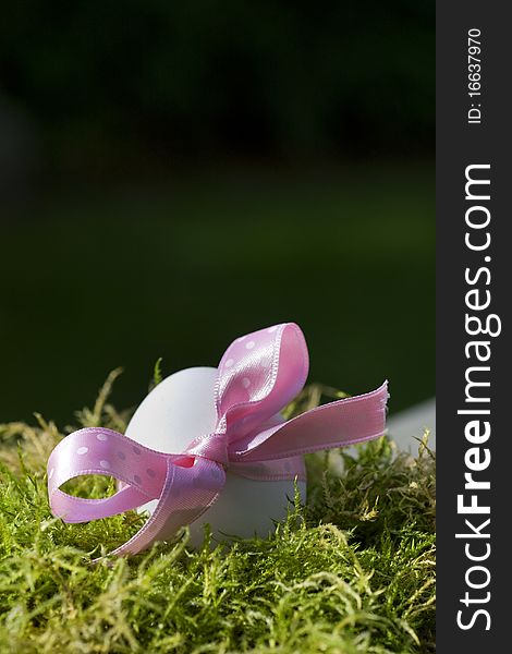Easter egg with pink bow in green moss