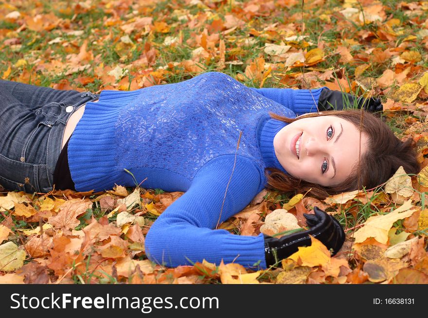 Beautiful young woman lying on the autumn leaves