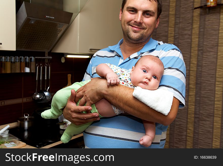 Portrait of young father is holding the baby on the kitchen. Portrait of young father is holding the baby on the kitchen