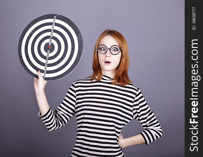 Red-haired girl with dartboard. Studio shot.