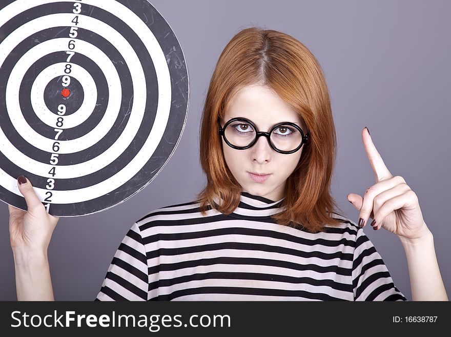 Red-haired girl with dartboard. Studio shot.