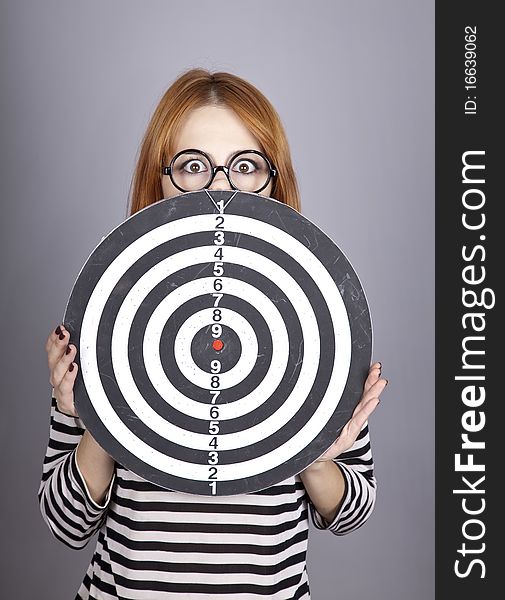 Red-haired girl with dartboard. Studio shot.