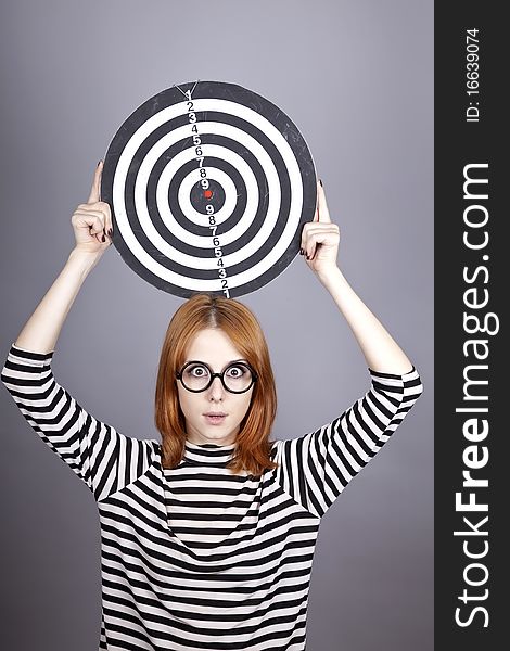 Red-haired girl with dartboard. Studio shot.