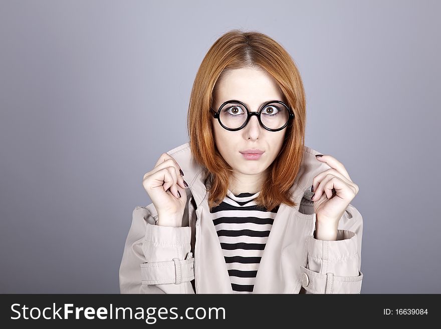 Young red-haired girl in glasses and cloak. Studio shot.
