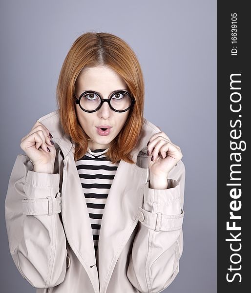 Young red-haired girl in glasses and cloak. Studio shot.