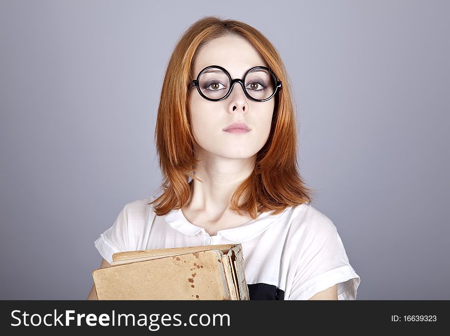 Funny red-haired girl with old book. Studio shot.