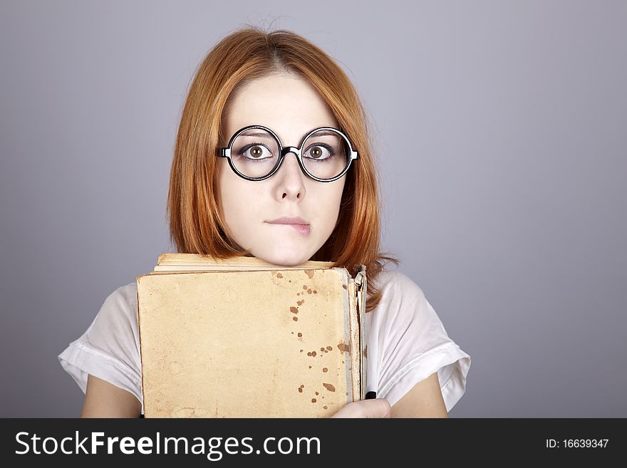 Funny red-haired girl with old book. Studio shot.