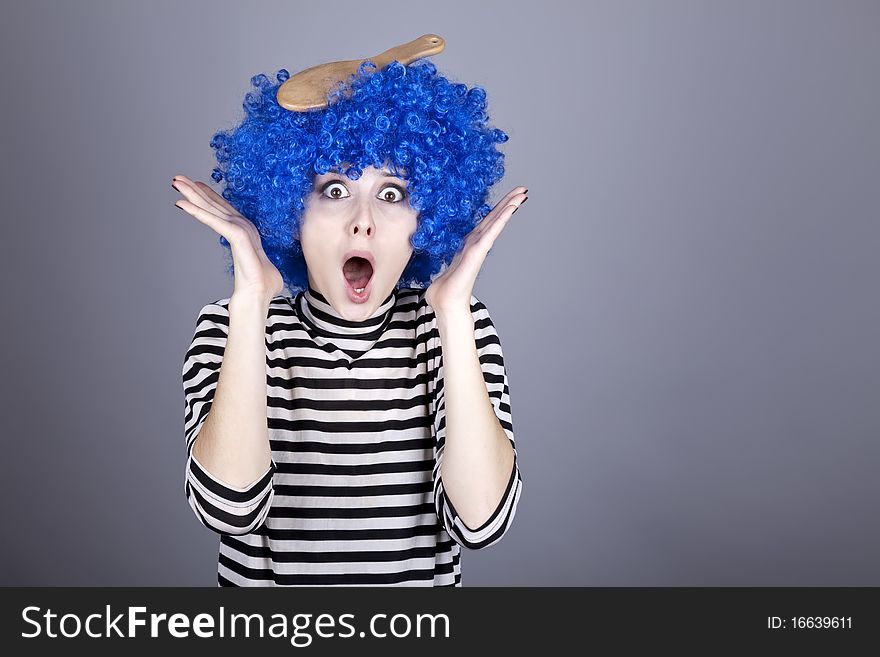 Surprised blue hair girl with stuck comb. Studio shot.