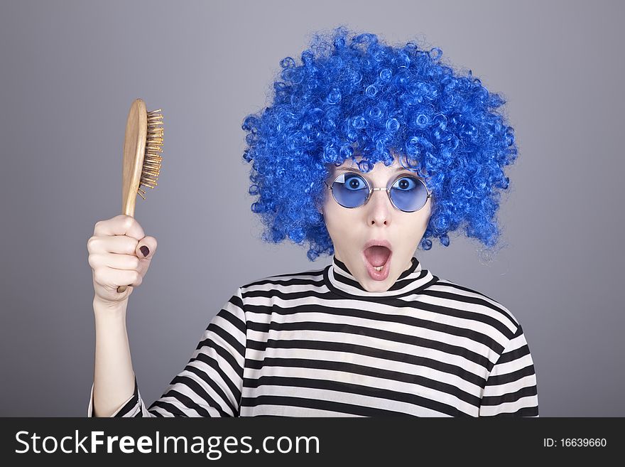 Surprised blue hair girl with comb. Studio shot.