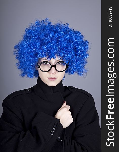 Funny blue-hair girl in glasses and black coat. Studio shot.