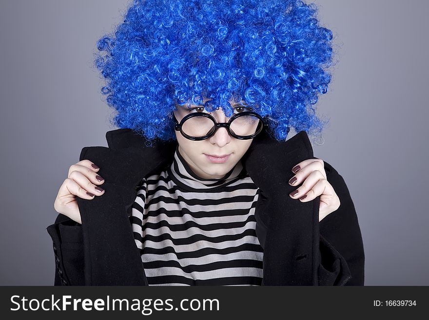 Funny blue-hair girl in glasses and black coat. Studio shot.