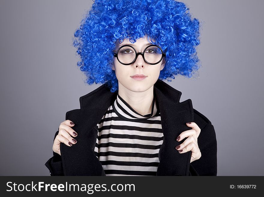 Funny blue-hair girl in glasses and black coat. Studio shot.