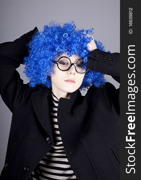 Funny blue-hair girl in glasses and black coat. Studio shot.