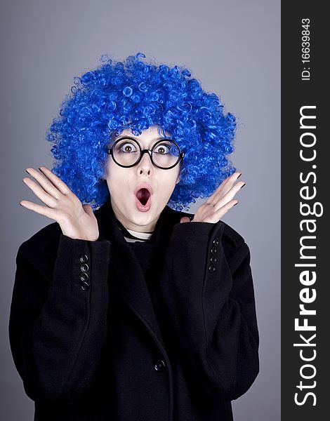 Funny blue-hair girl in glasses and black coat. Studio shot.