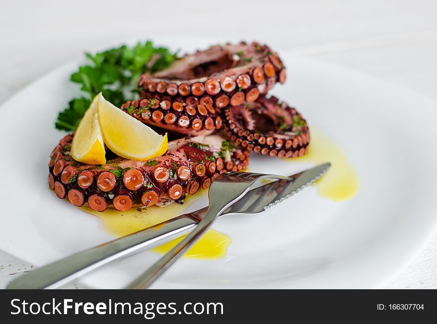 Delicious octopus salad with dressing, lemon and parsley on white background. Healthy eating. Seafood cooking