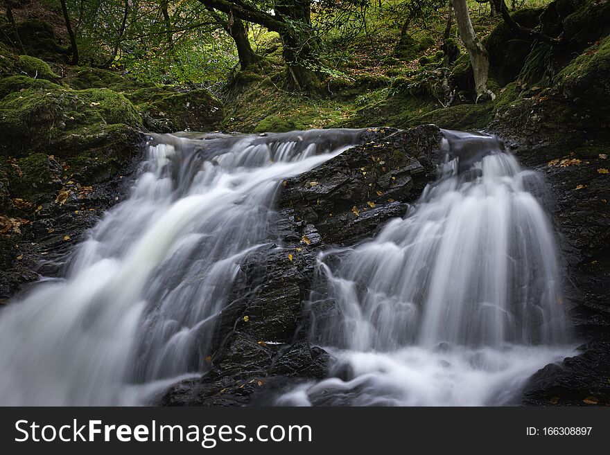 Tranquil autumn woodland scene with waterfall in Scottish highlands