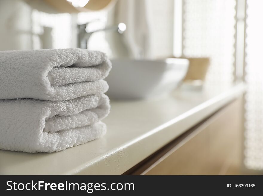 Stack of clean towels on countertop in bathroom