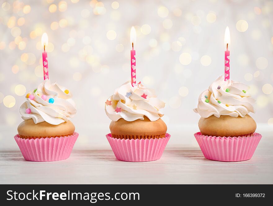 Birthday cupcakes with candles on table. Bokeh effect