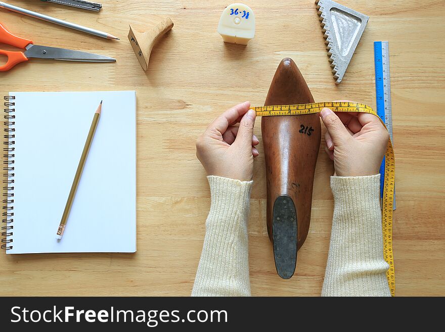 Top view of measuring tape on wooden last shoe on wood background with copyspace