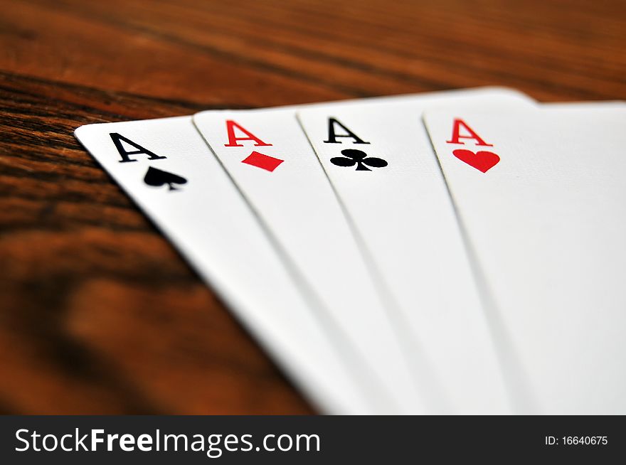 A group of four playing card aces on a stained oak wooden table. A group of four playing card aces on a stained oak wooden table.