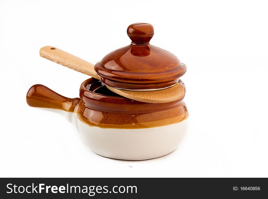 Brown soup crock with wooden spoon on white background