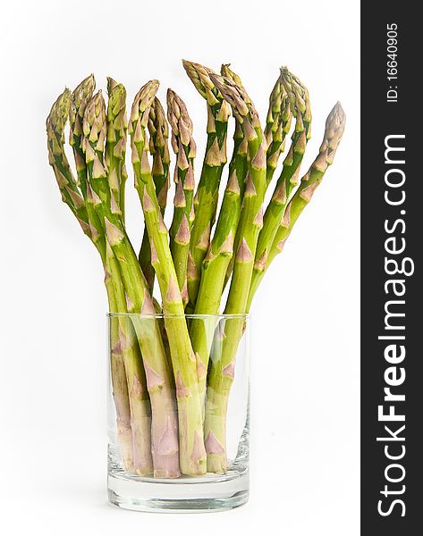 Bunch of fresh green asparagus standing in a glass on a white background
