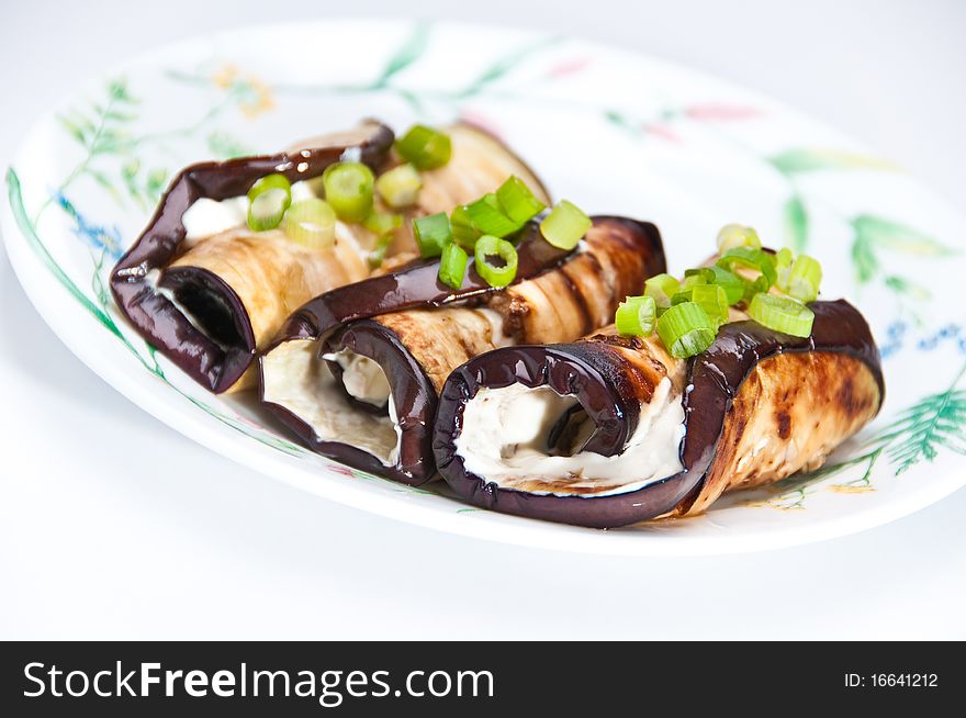 Eggplant rolls filled with goat cheese and decorated with young onion accompanied by a fork. Eggplant rolls filled with goat cheese and decorated with young onion accompanied by a fork