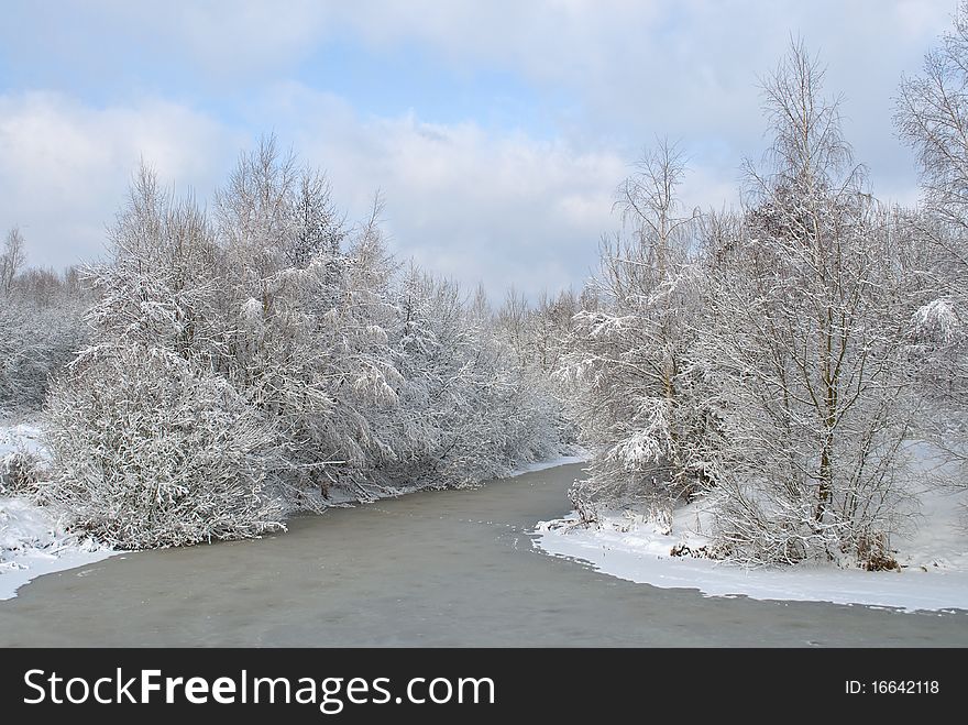 Snow-covered landscape with the river at the winter. Forest in the Snow. Trees in the Snow.